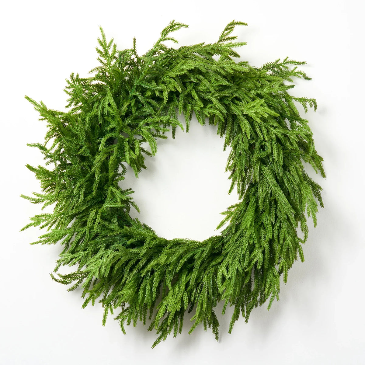 Green faux pine Christmas wreath with dense needle tips, close-up view.