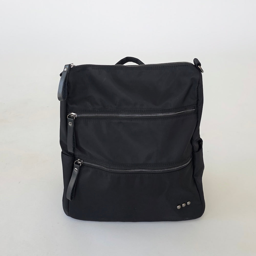Nylon backpack purse in black, front view with two zip pockets and metal details