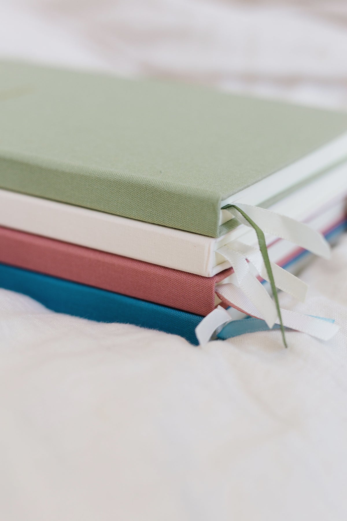 Linen notebook set with tied ribbon, stacked in green and blue covers