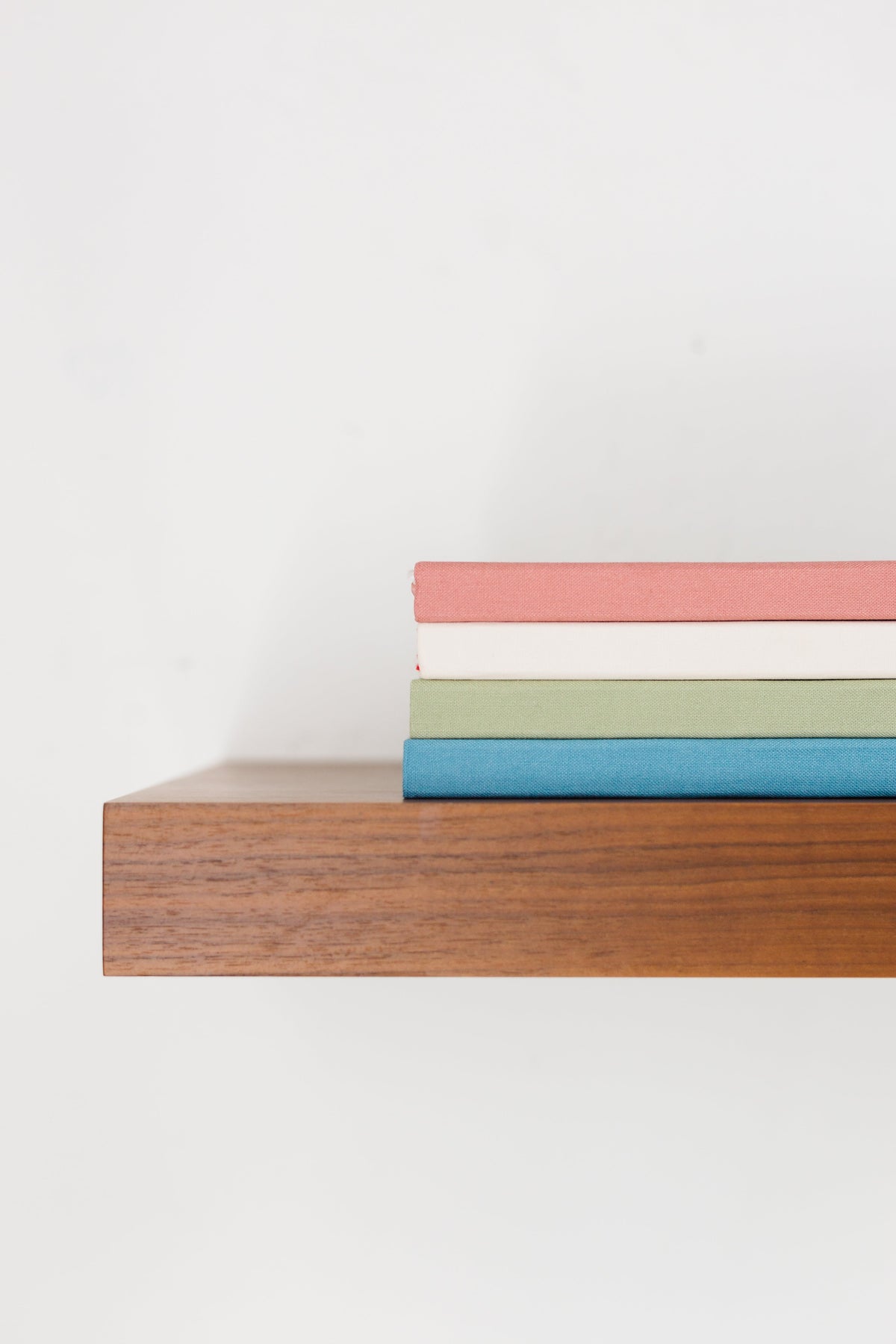 Side view of stacked notebooks in pink, green, and blue