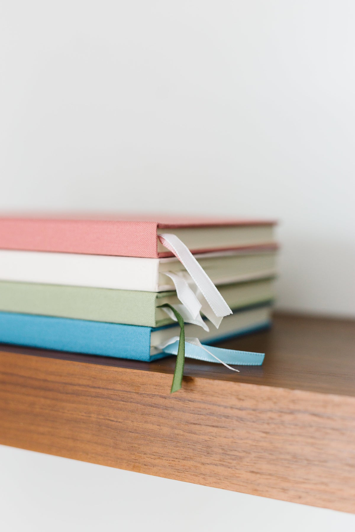 Stack of colored notebooks with ribbon ties on a wooden surface