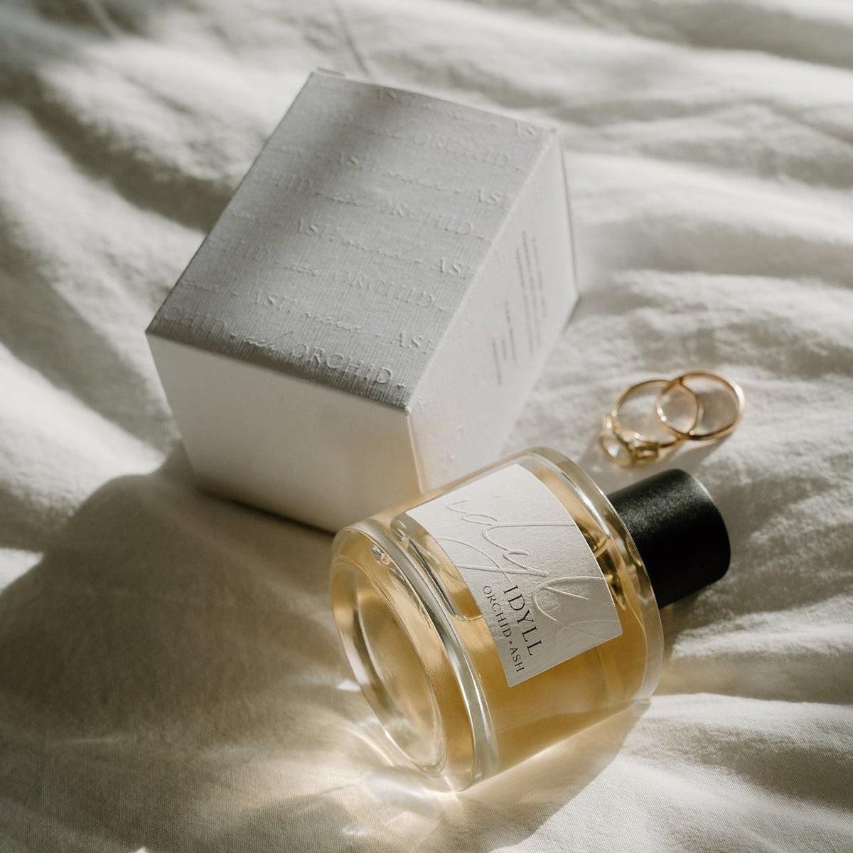 IDYLL perfume bottle with black cap and matching gift box on fabric