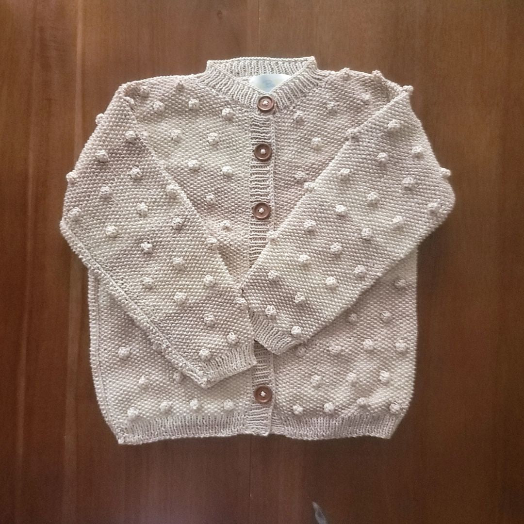 Cream knit cardigan with textured dot pattern and brown button placket