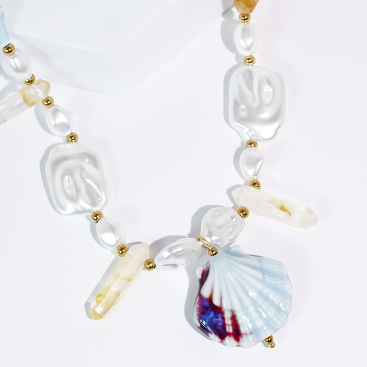 Pearl-like beaded necklace with gold spacers and seashell, cross, and conch charms