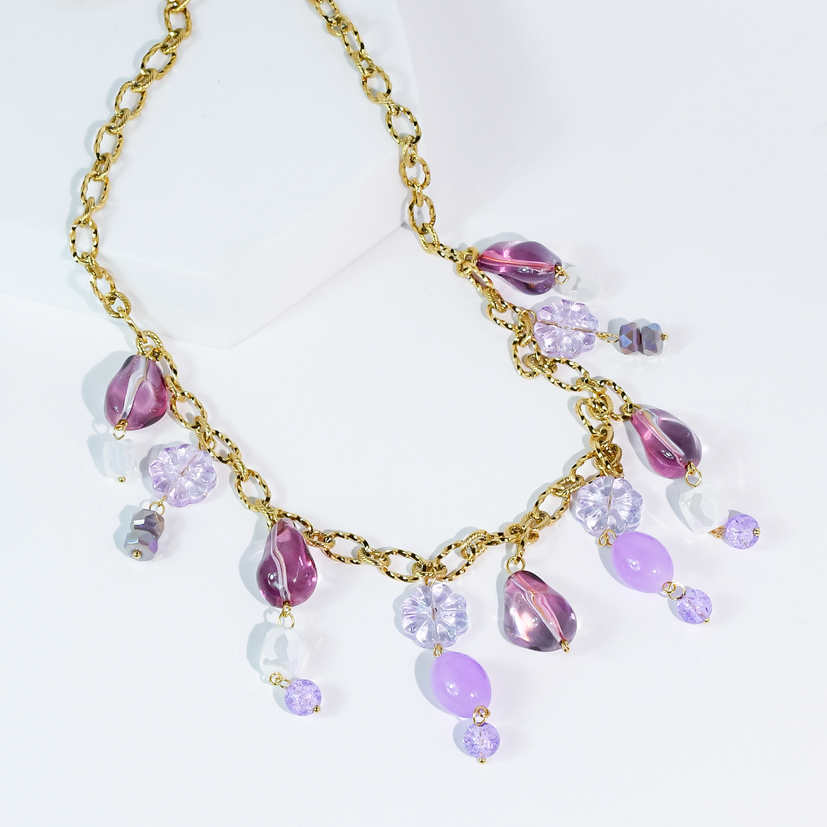 Gold beaded necklace with purple and pink teardrop charms and crystal-like drops