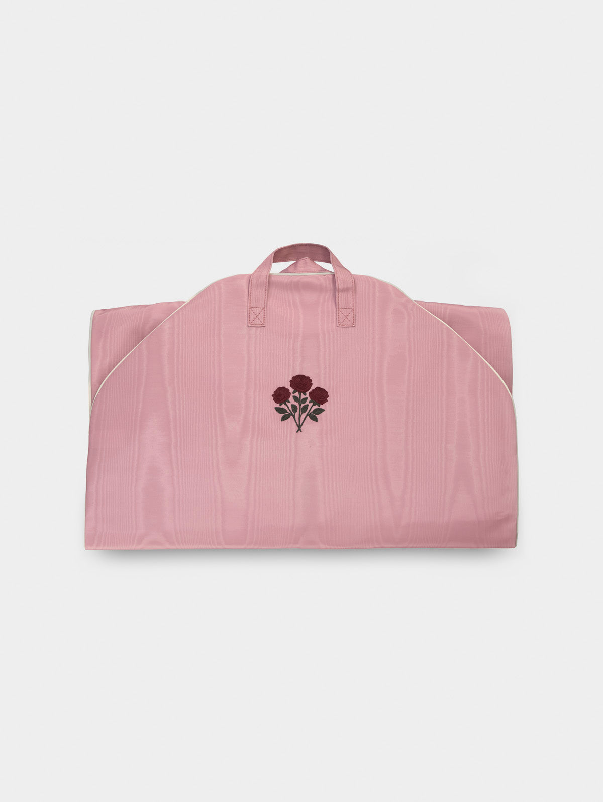 Folded pink garment bag with top handles and floral embroidery