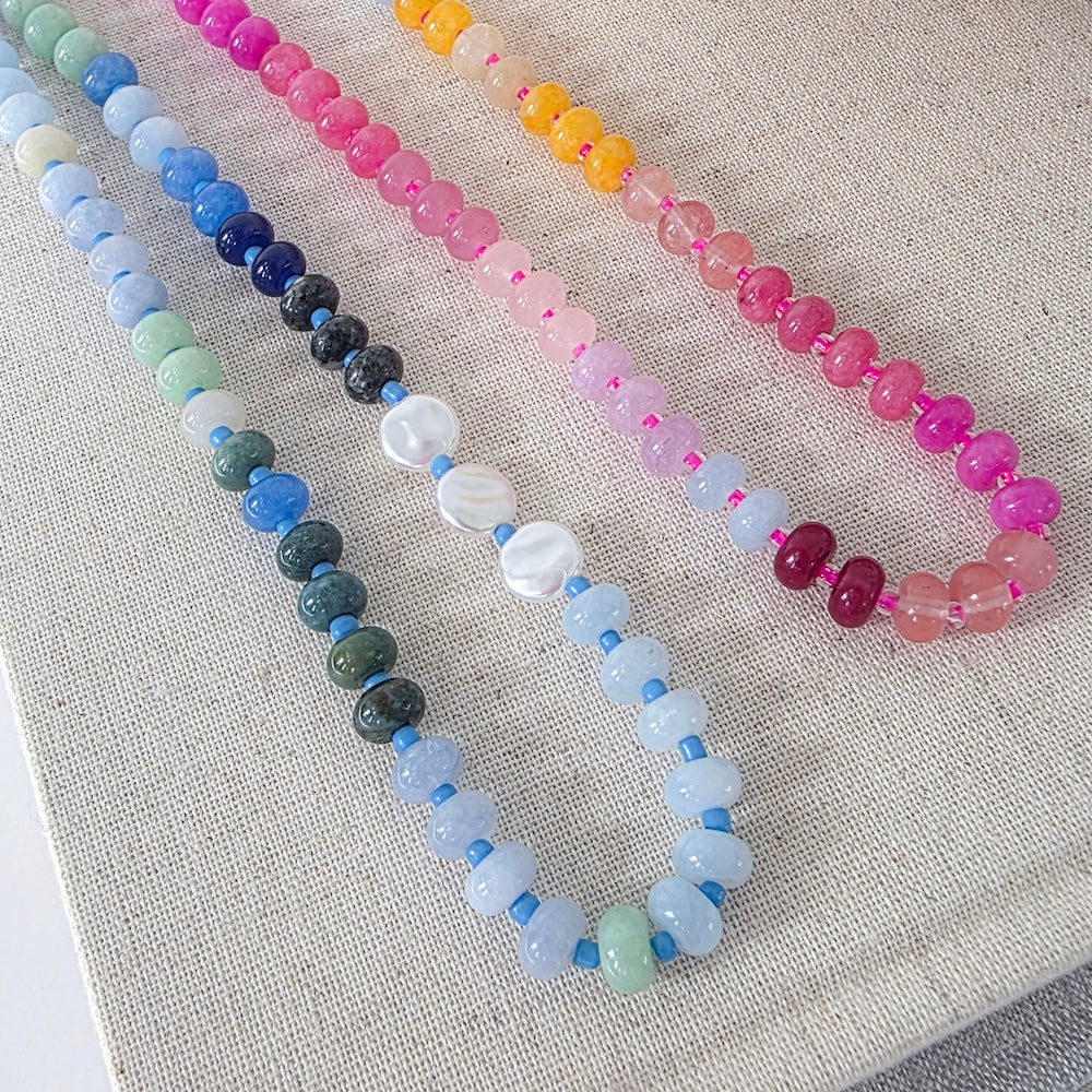Close-up of waterproof ombre beaded necklaces with blue, pink, and orange mixed beads