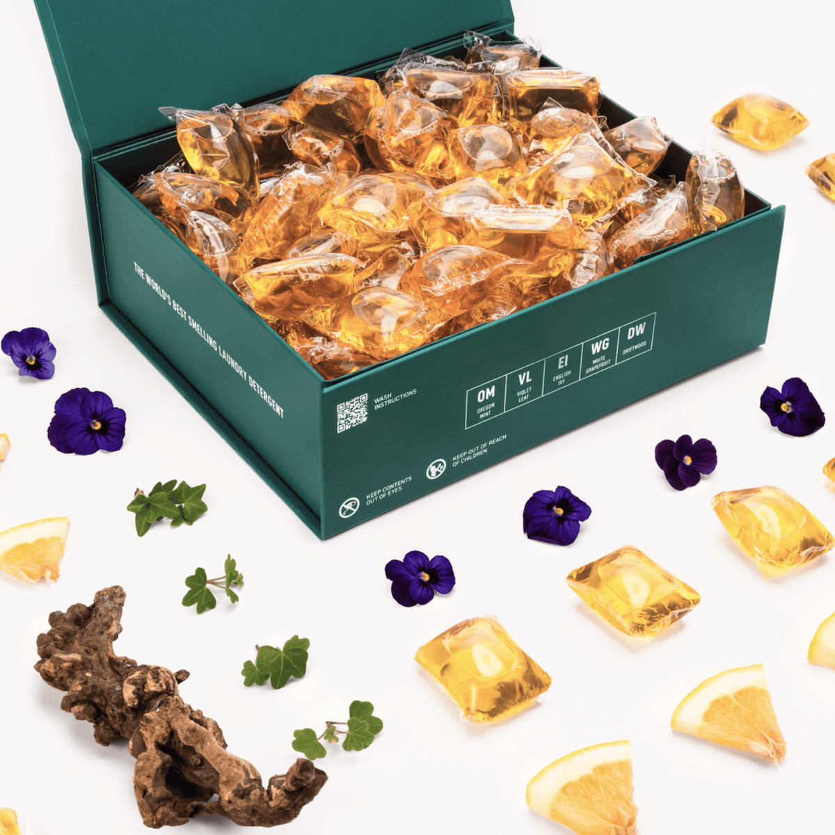 Open teal box filled with amber gel detergent pods with scattered pods around