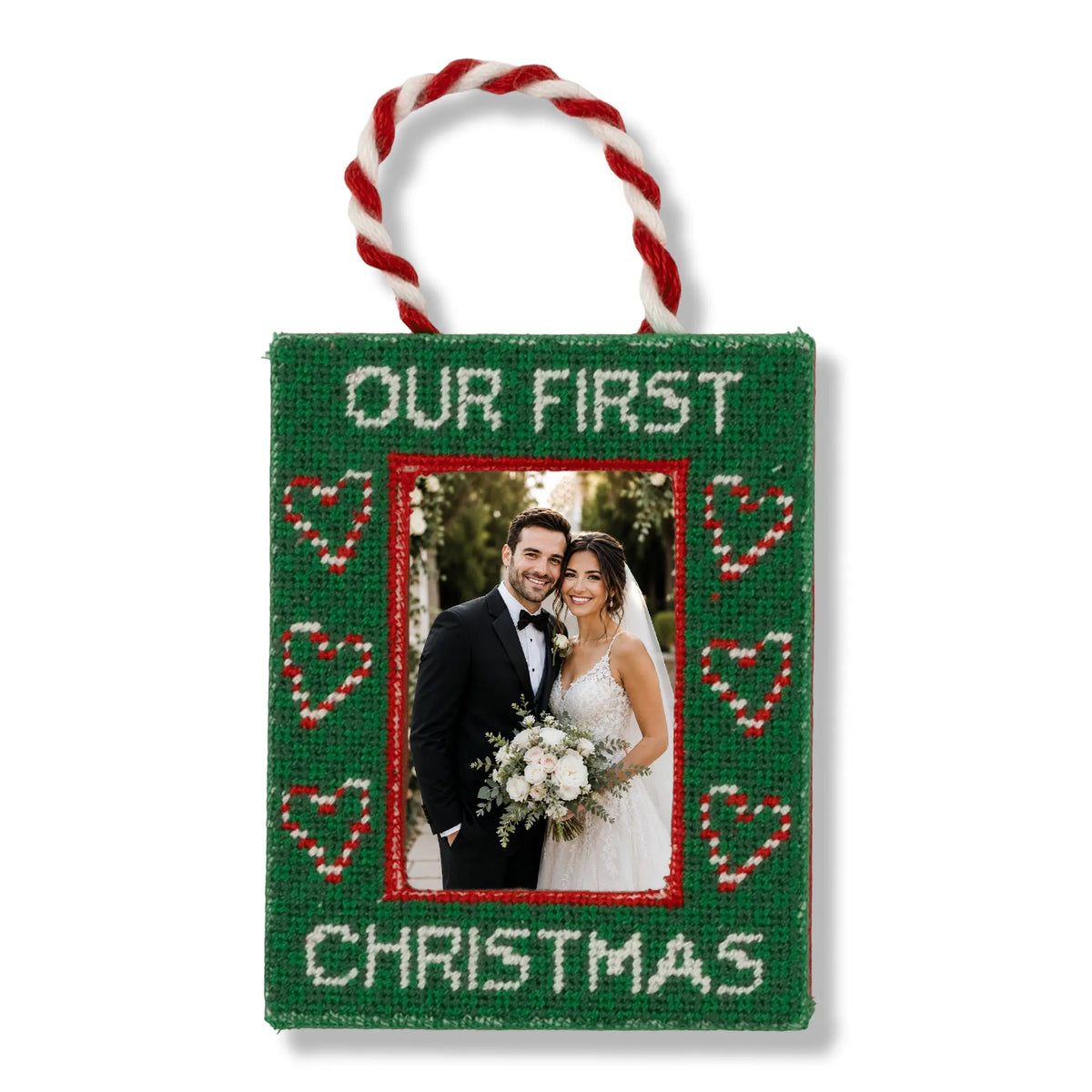 Green fabric photo frame ornament with red-and-white braided loop, “Our First Christmas”