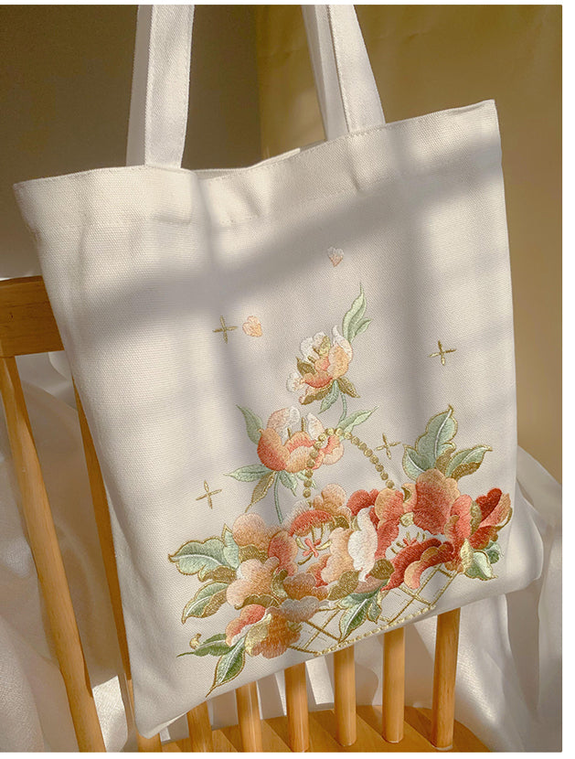 White tote bag with long handles and colorful flower basket embroidery with crosses.