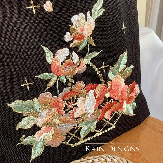 Black tote bag featuring detailed floral basket embroidery and cross motifs.