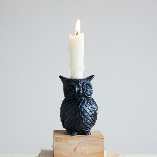Black resin owl taper candle holder with lit candle on wood block
