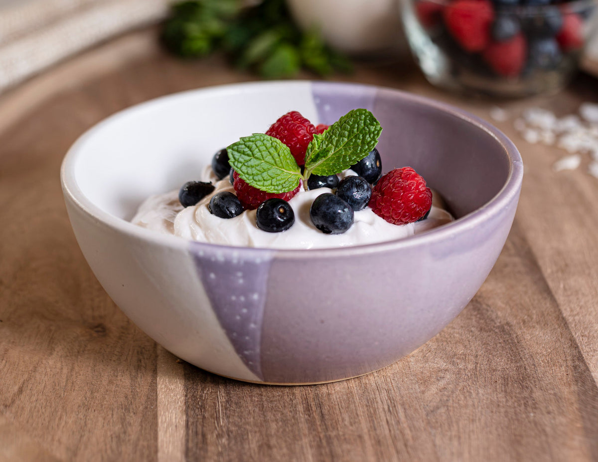 Purple and white stoneware soup bowl with berry fruit and mint