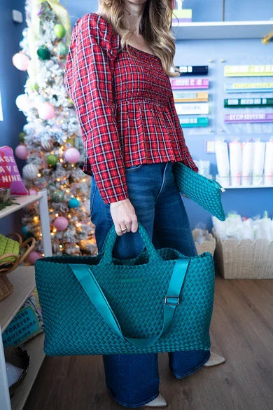 Woven carryall tote with tile pouch, held at hip by woman, textured woven fabric