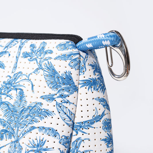 Printed toiletry pouch corner with zip, blue braided strap, and metal D-ring