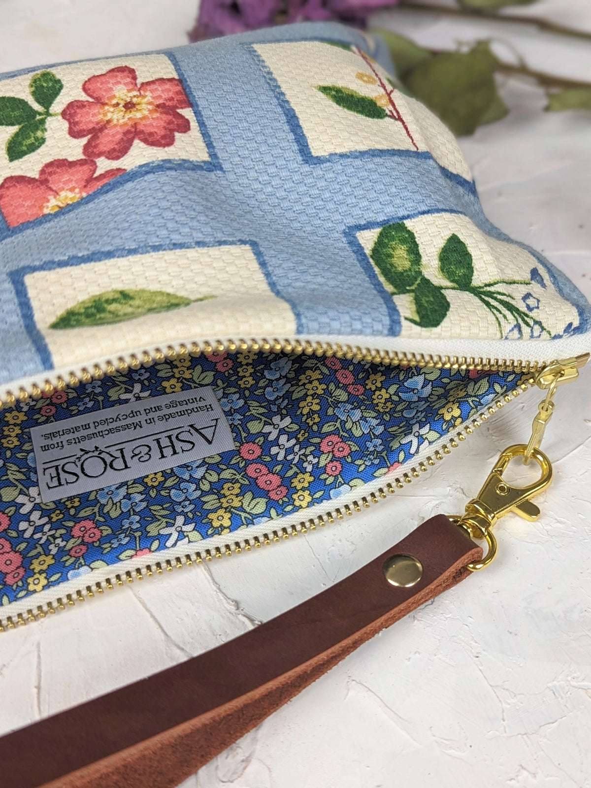 Wristlet purse showing gold zipper pull and floral bird patchwork fabric