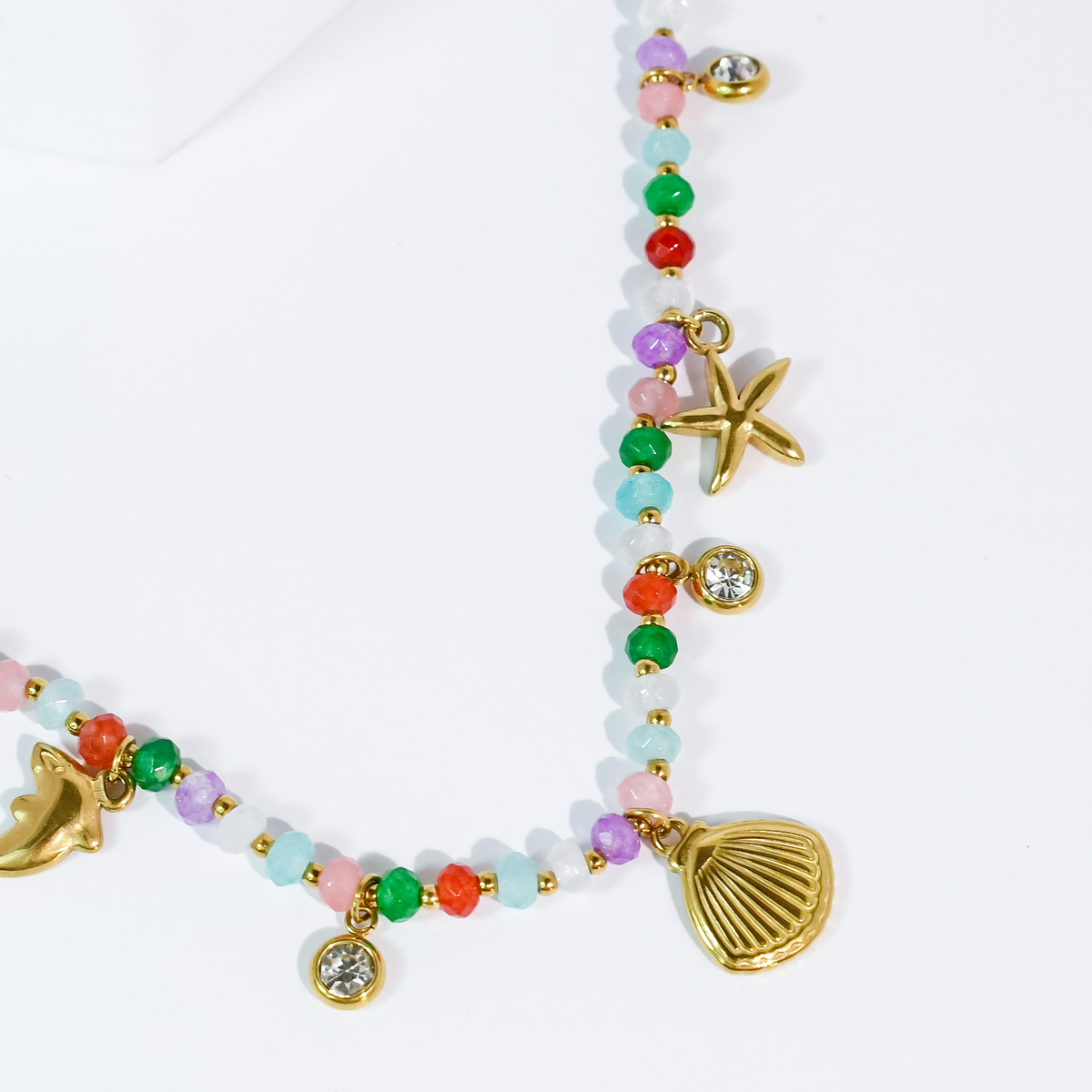 Colorful beaded necklace with gold-tone charms: shell, starfish, dolphin, round crystal