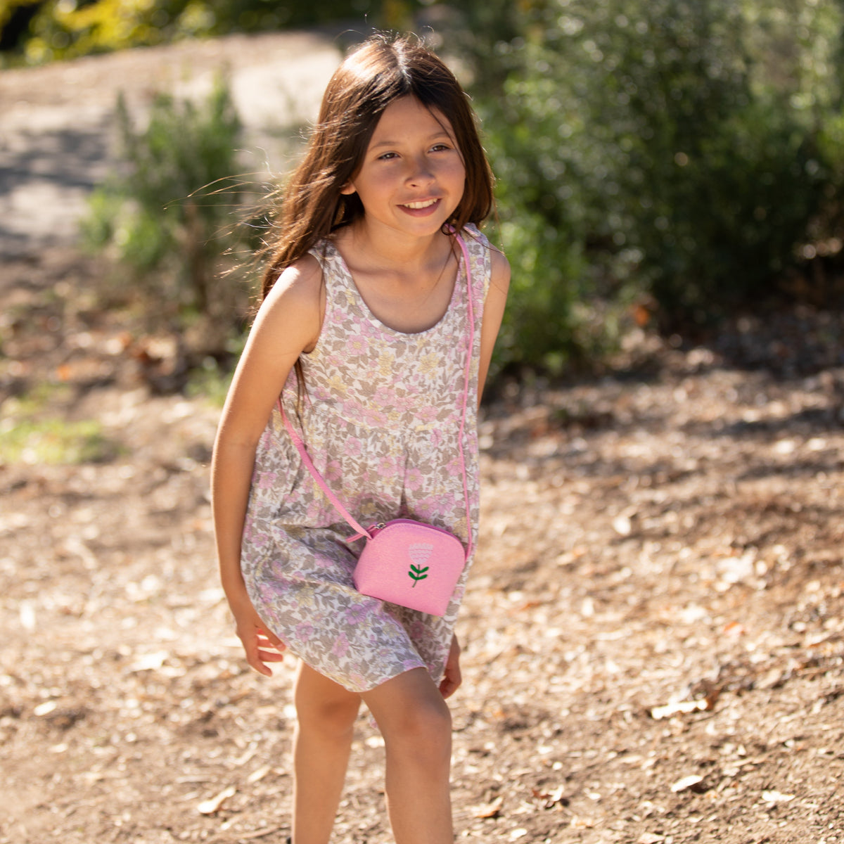 Pink glitter flower-embroidered purse worn crossbody by a child