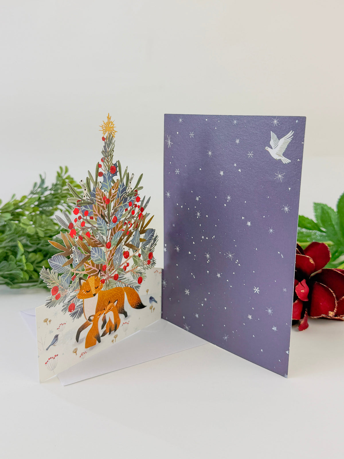 Open lasercut Christmas card showing a pop-up tree scene and starry inner panel
