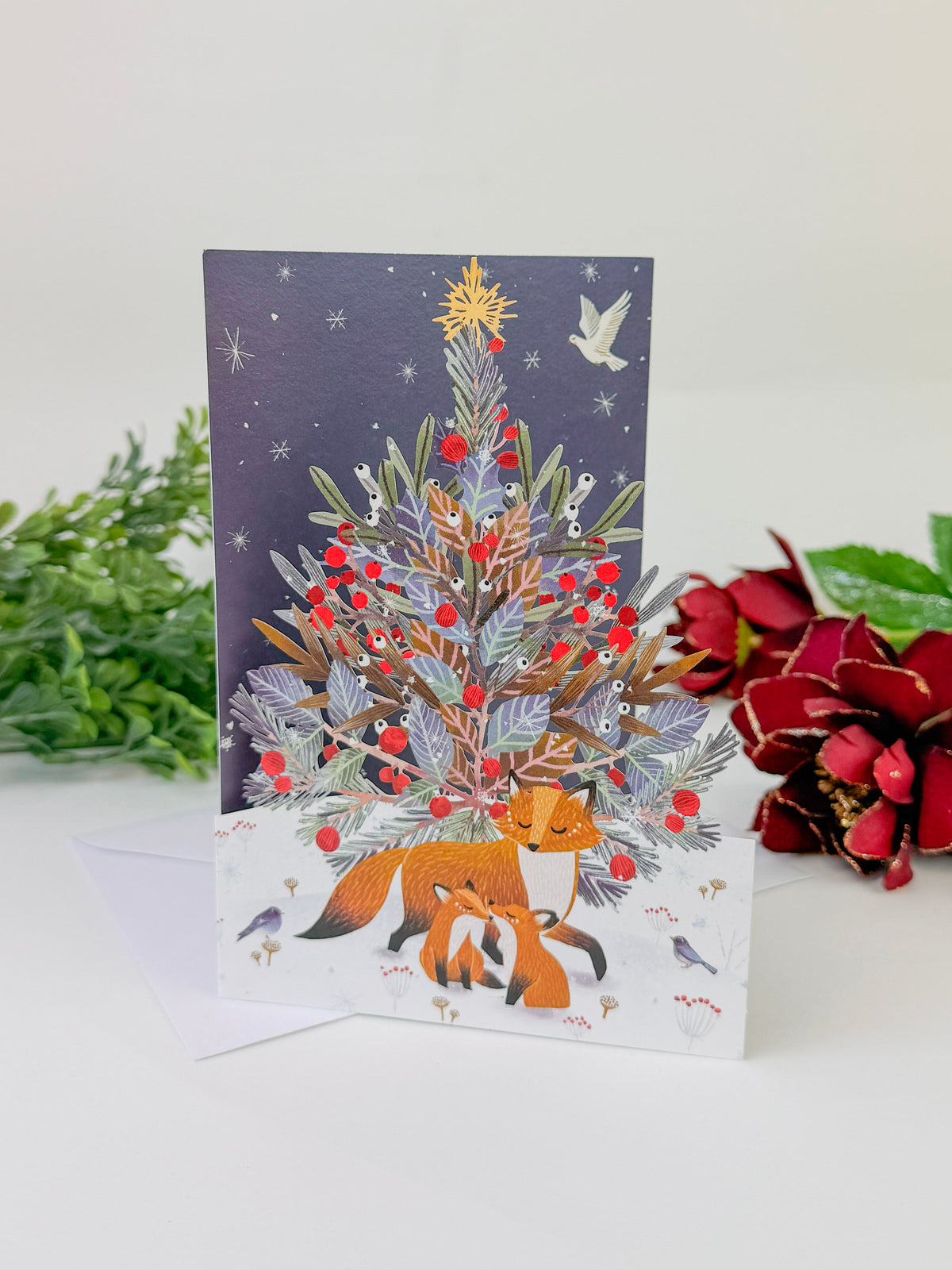 Lasercut Christmas card with a colorful tree, foxes, birds, and paw prints