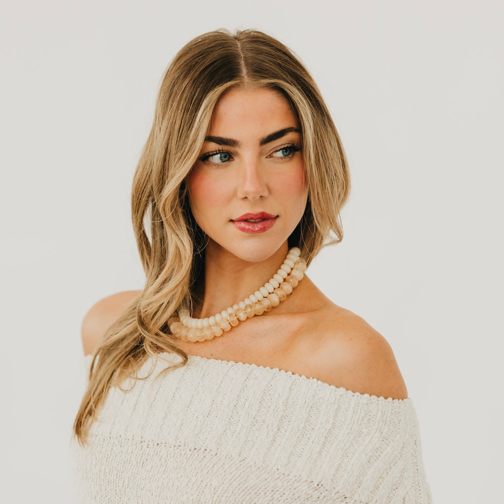 Ivory resin beaded necklace worn at the neck with short gold clasp chain