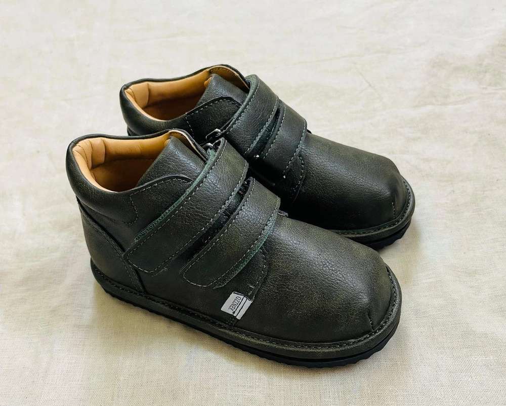 Pair of kids black sneakers with two hook-and-loop straps and padded collar