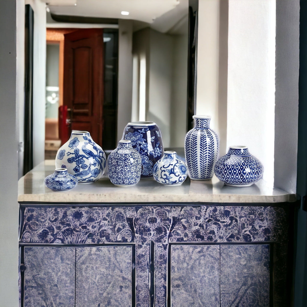 Blue-and-white ceramic vase set displayed on a ledge in a hallway