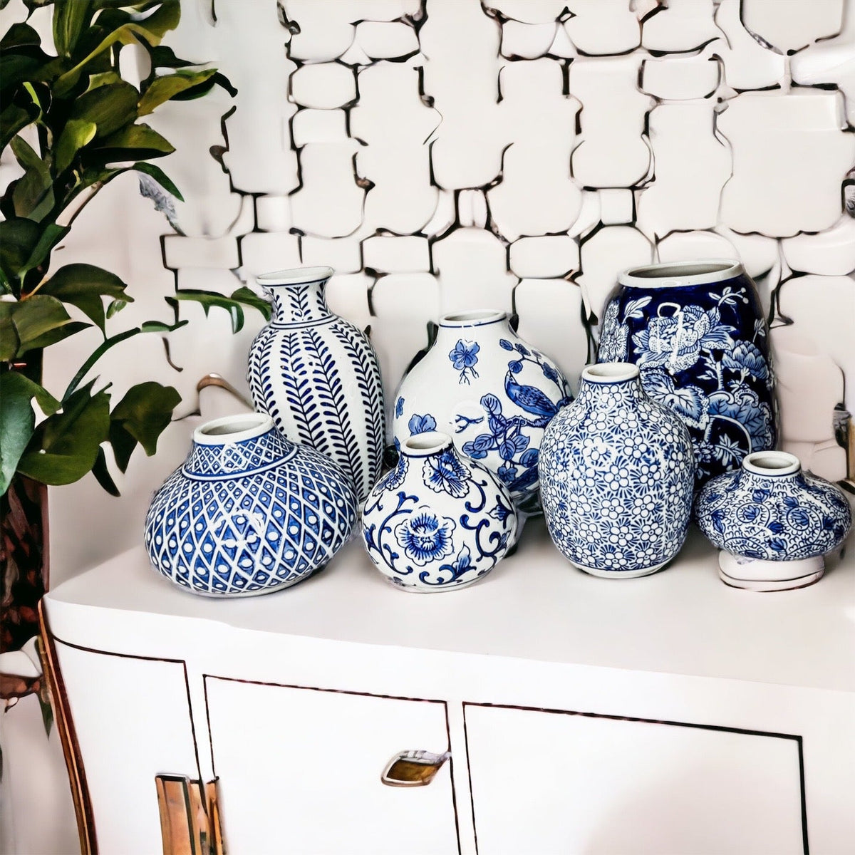Blue-and-white ceramic vases arranged on a white cabinet, varied patterns