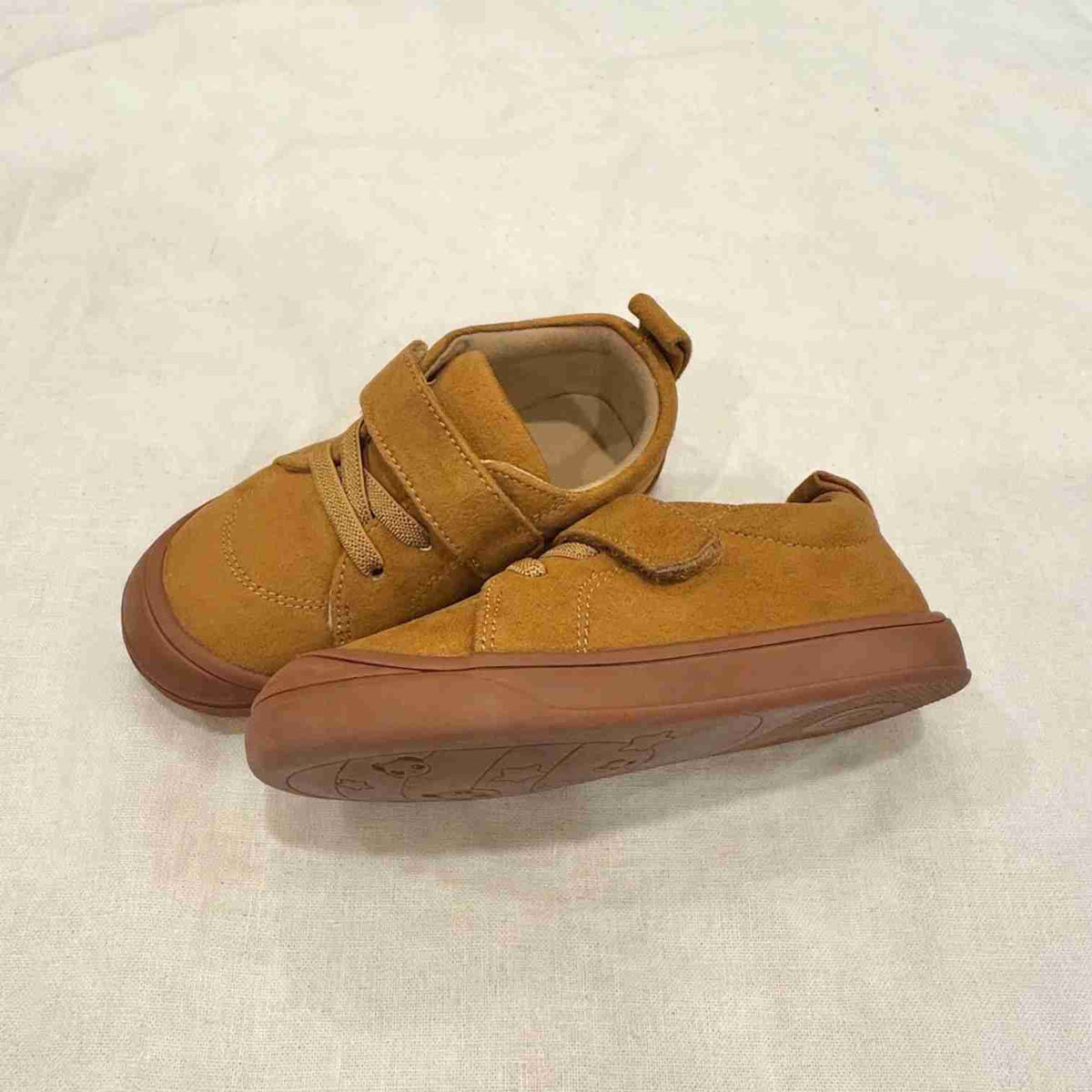 Tan suede kids' sneakers showing side profile and rubber sole