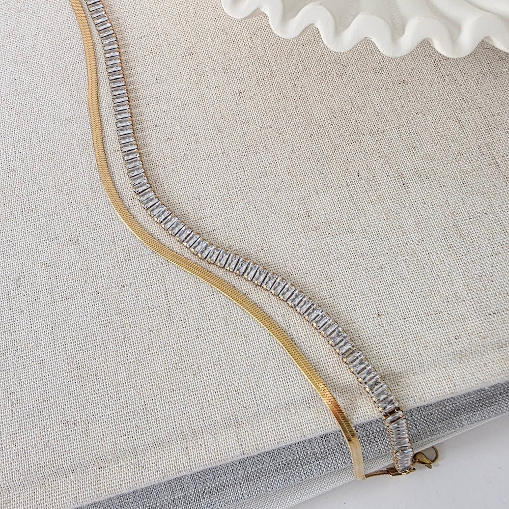 Layered gold necklace with baguette crystal strand and smooth gold chain