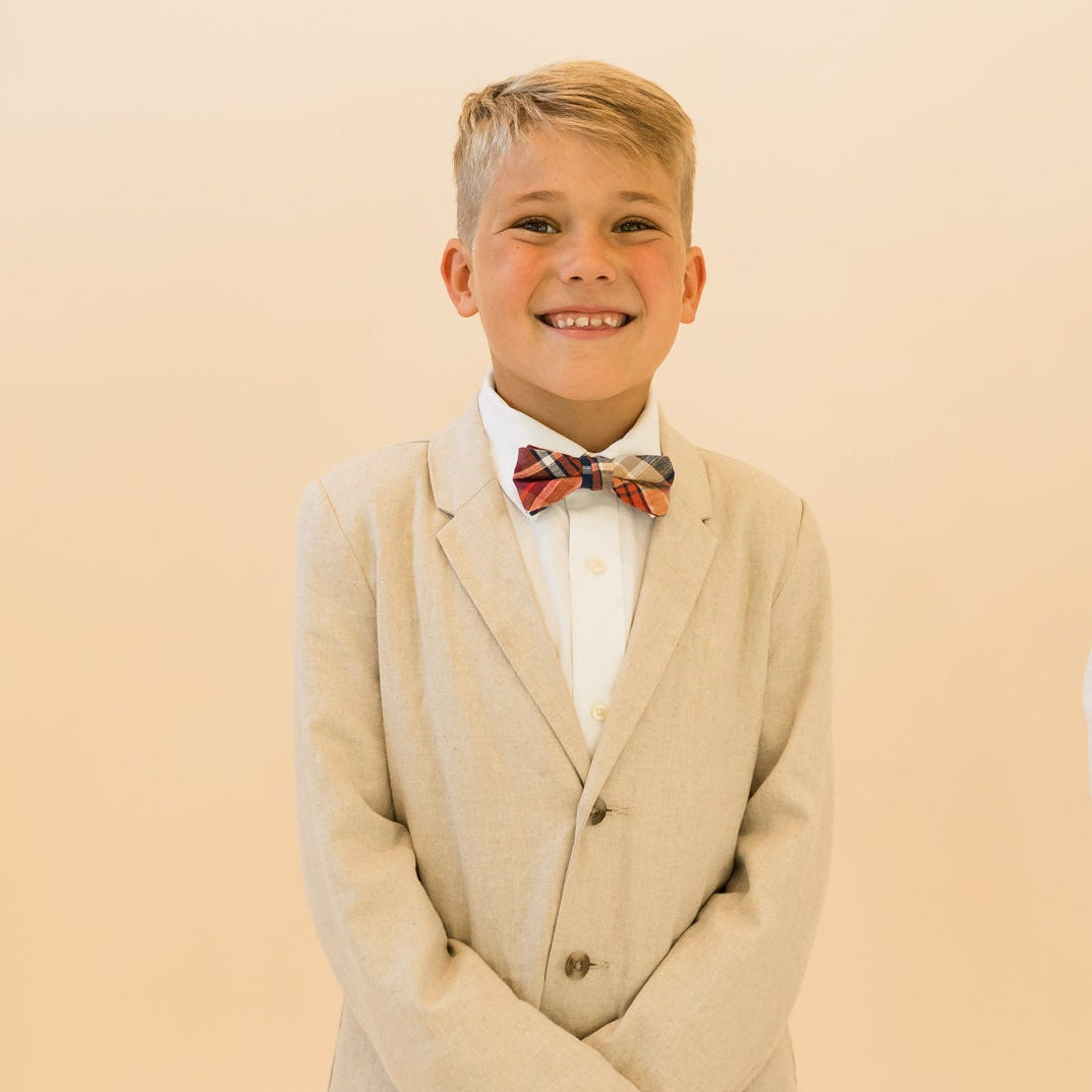 Boys plaid bow tie worn with white shirt and beige suit jacket