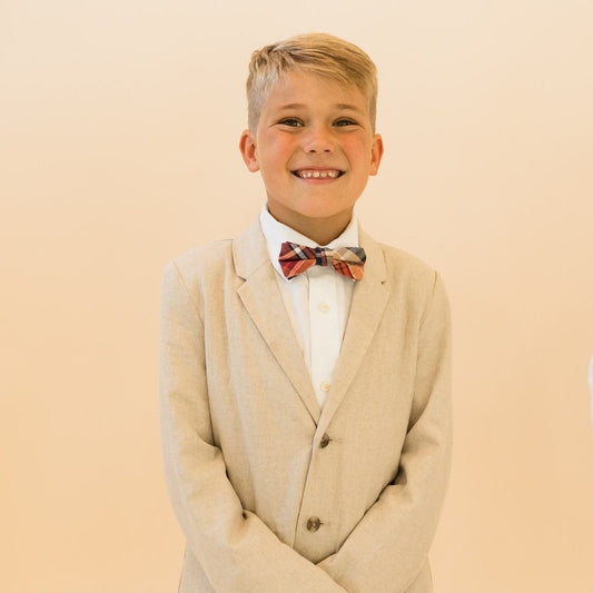 Boys plaid bow tie worn with white shirt and beige suit jacket