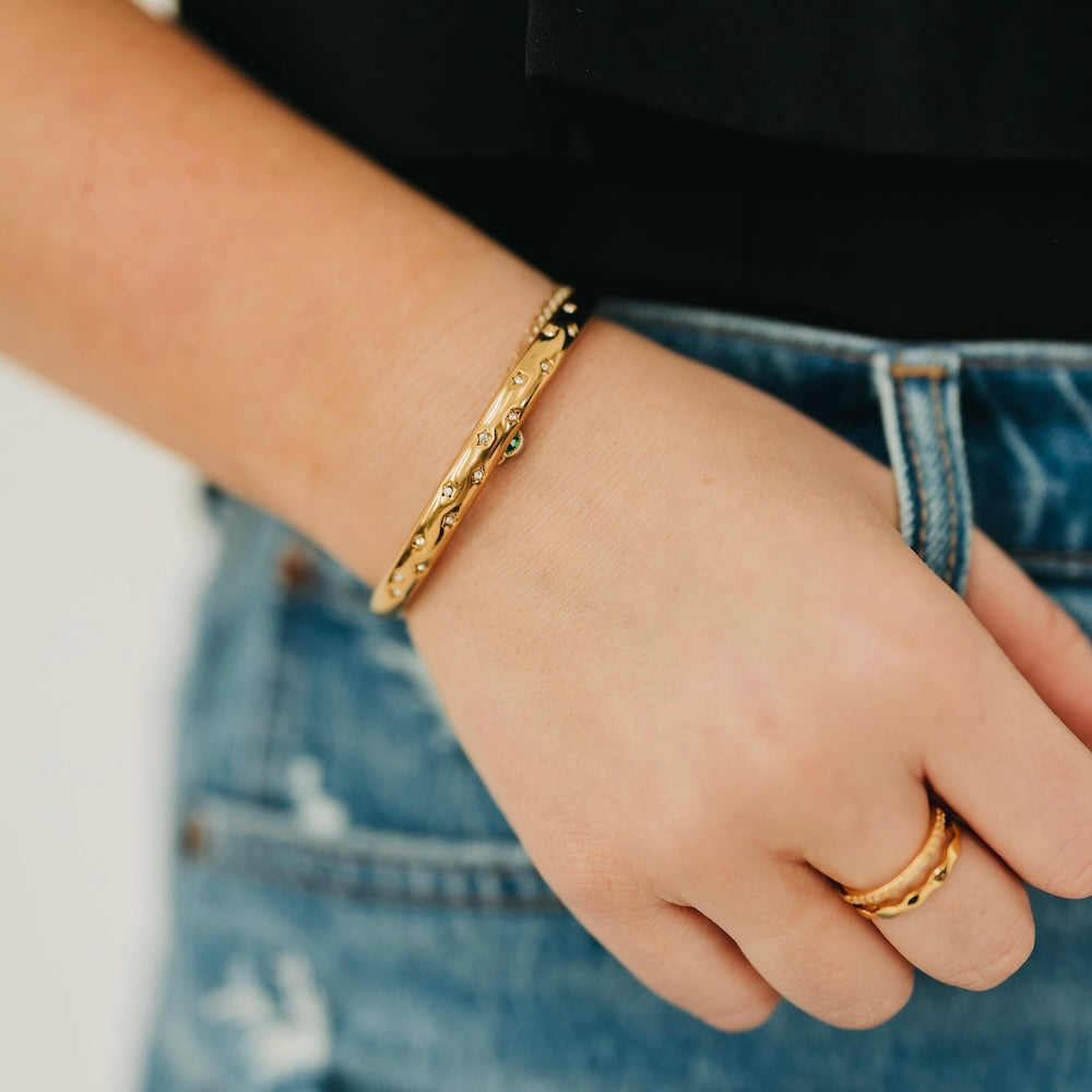 Gold-tone sparkle cuff bangle with small clear stones, worn on wrist