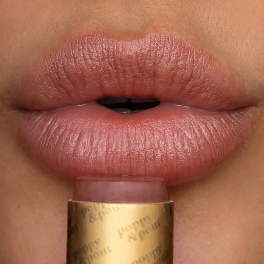Debbie lip tint on lips in rose-pink shade with gold applicator visible