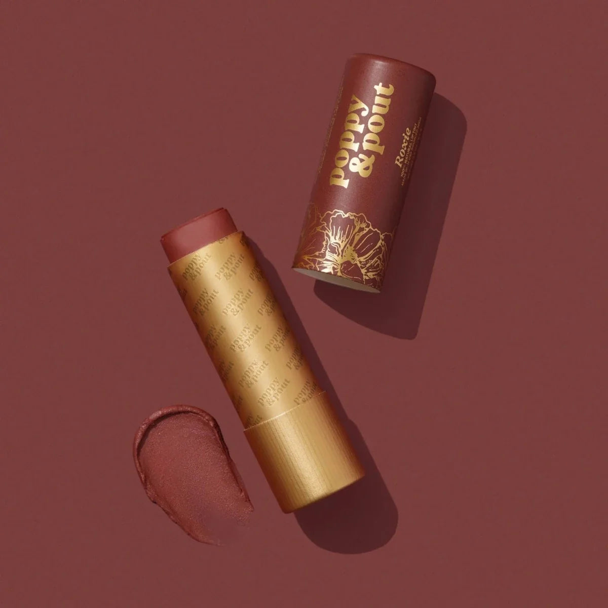 Lip tint tube in gold with brown cap; open lip swatch in mauve-rose