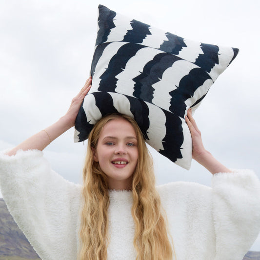 Navy and off-white throw pillow with zigzag crescent pattern, held overhead