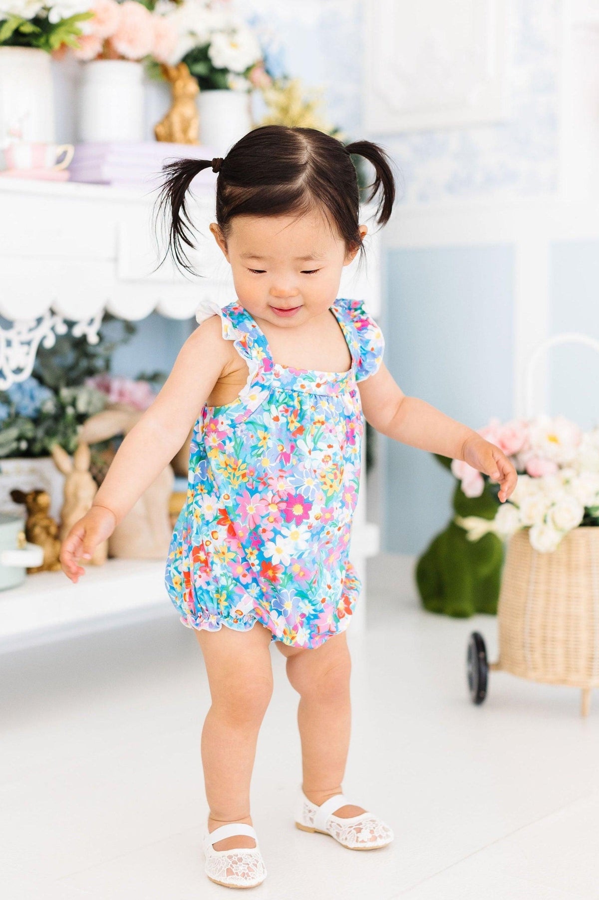 Multicolor floral cross-back romper with ruffled sleeves, worn by child