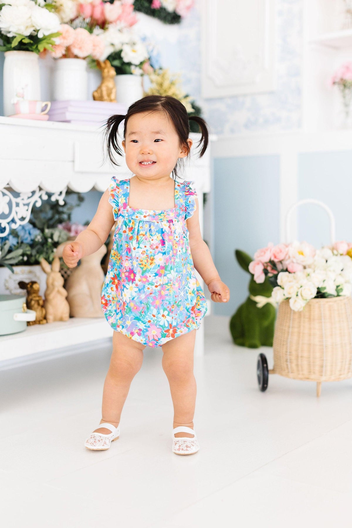 Front view of multicolor floral cross-back romper with ruffled shoulder straps