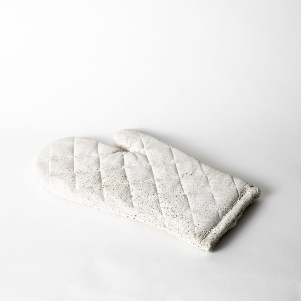 White terrazzo quilted oven mitt with diamond stitching and stitched edge.