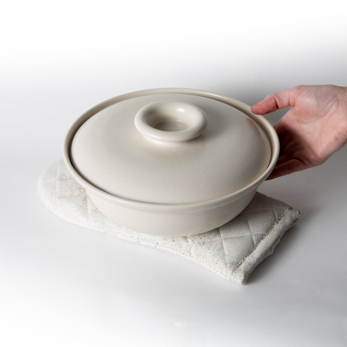 White terrazzo quilted oven mitt holding a covered pot with a secure grip.