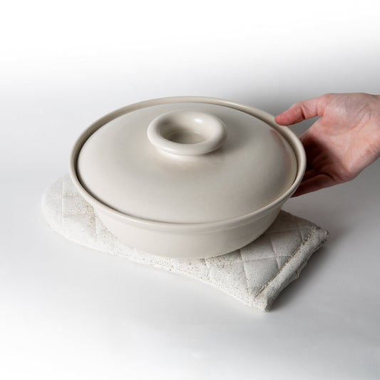 White terrazzo quilted oven mitt holding a covered pot with a secure grip.