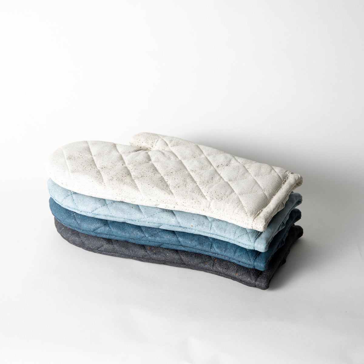 Stacked quilted oven mitt trivets with cream, light blue, and dark gray layers