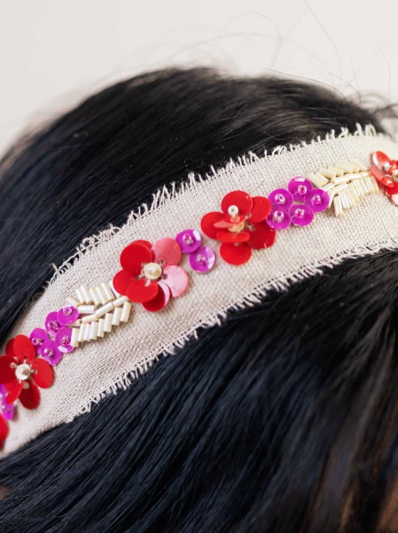 Close-up of cream beaded headband with red, purple, and gold flower details