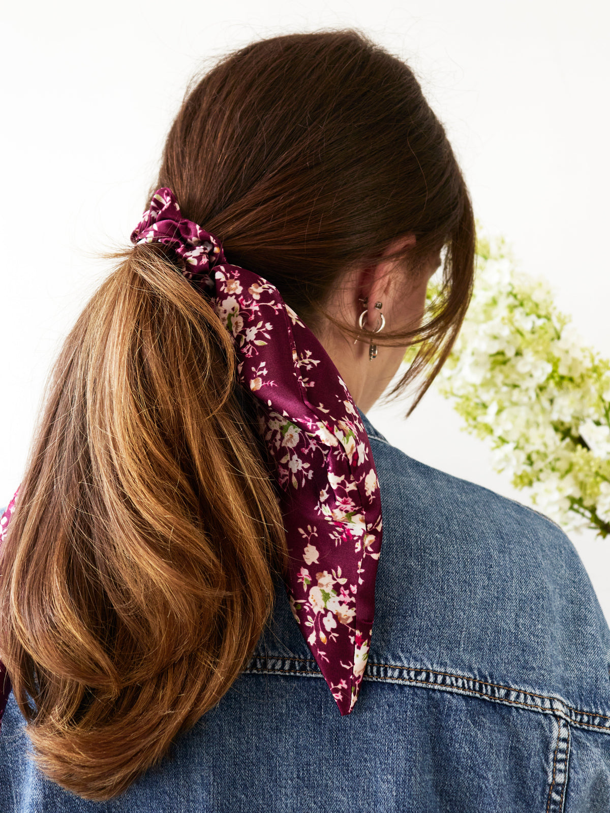 Purple satin floral scarf scrunchie in a bun with long knot and tails