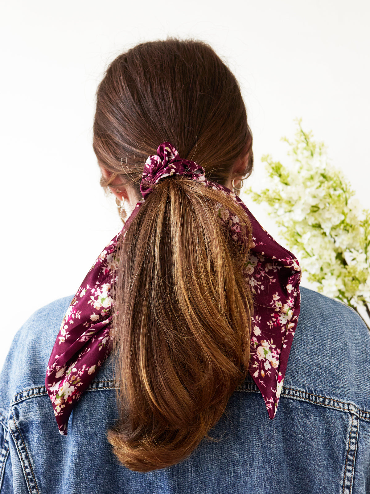 Purple satin floral scarf scrunchie tied around hair with long trailing ends