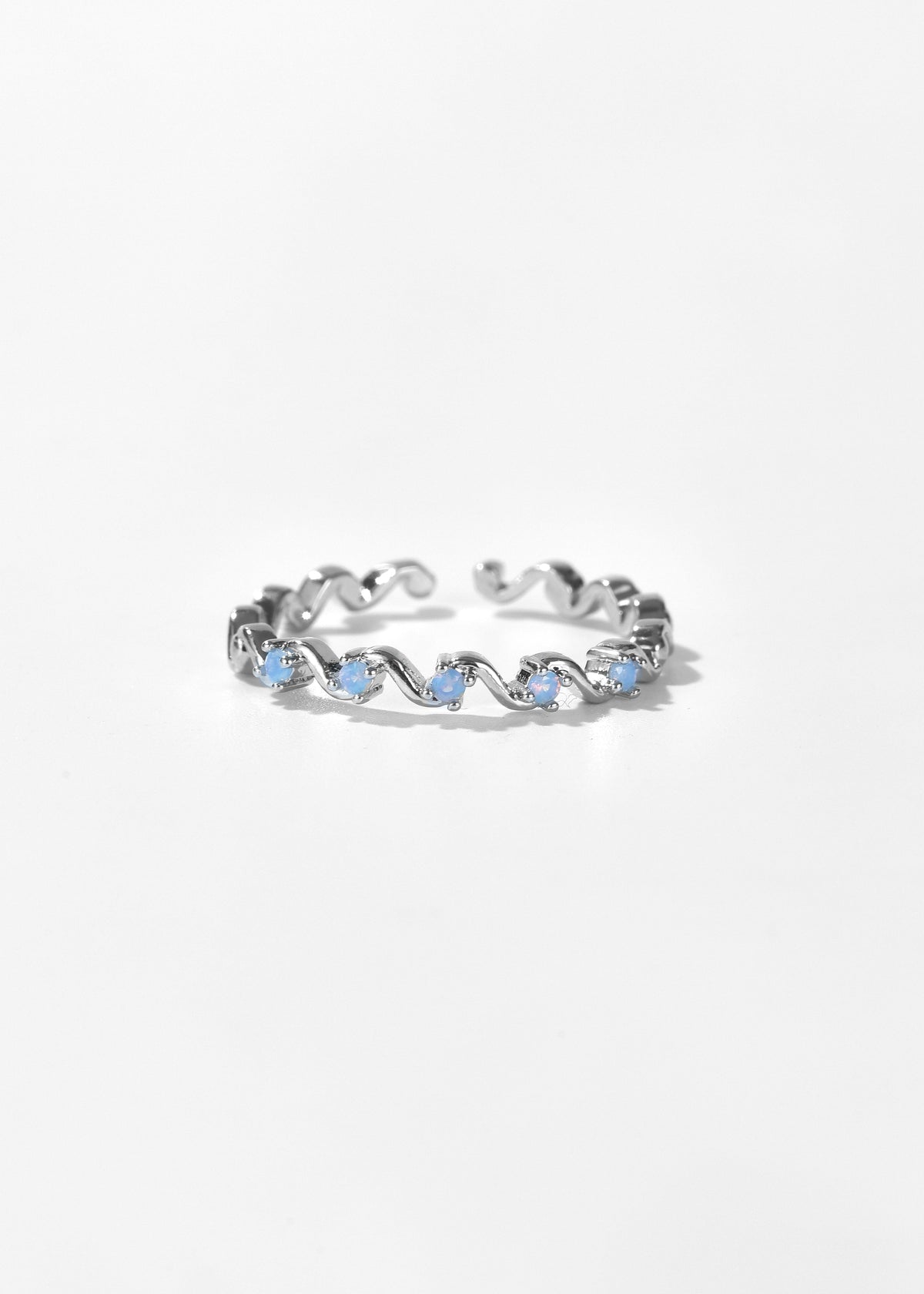 Silver wavy ring set with small pale blue stones along the band.