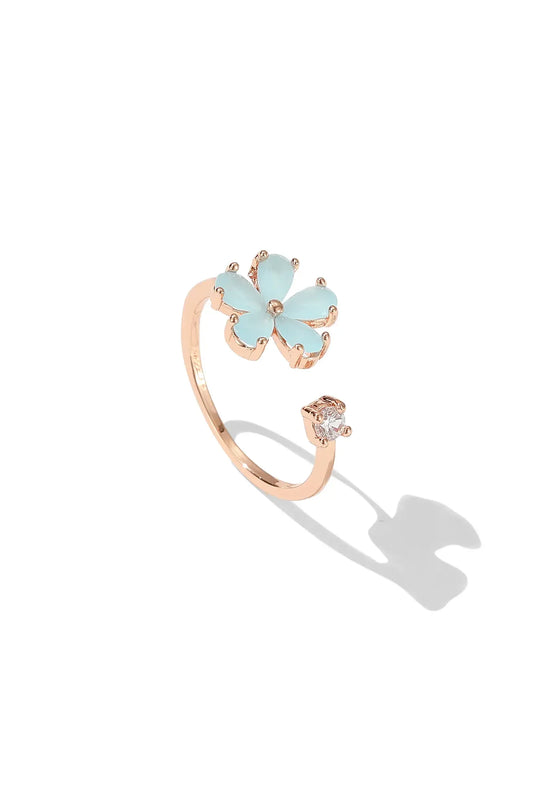 Open gold-tone ring with a light blue flower and a clear accent stone