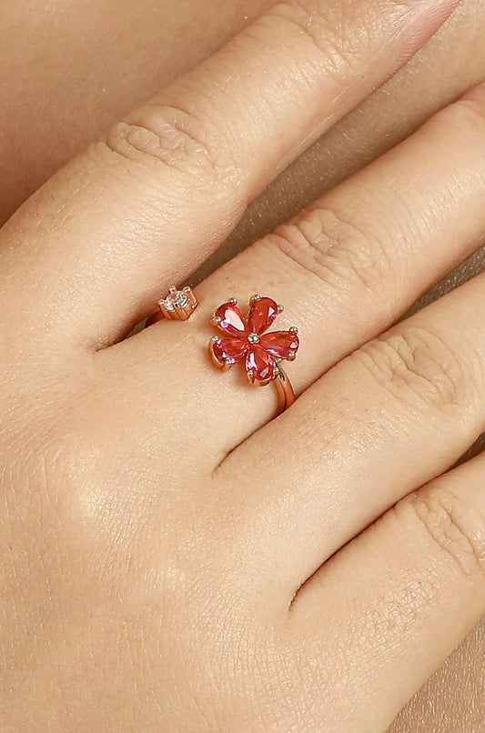 Gold-tone open ring with a red flower and a clear accent stone, worn on a hand