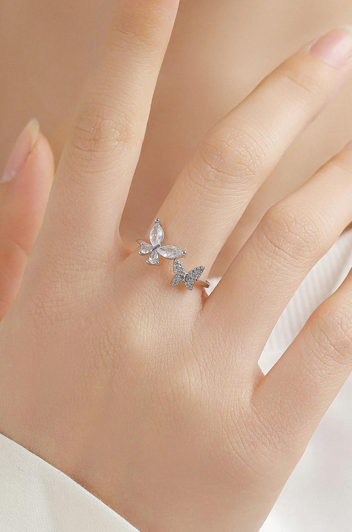 Open butterfly ring worn on a finger, with two crystal butterfly charms