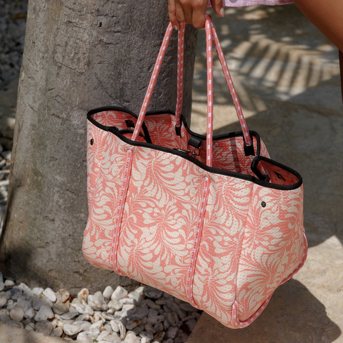 Pink palm-leaf tote with front zip pocket, black trim, and pink rope handles